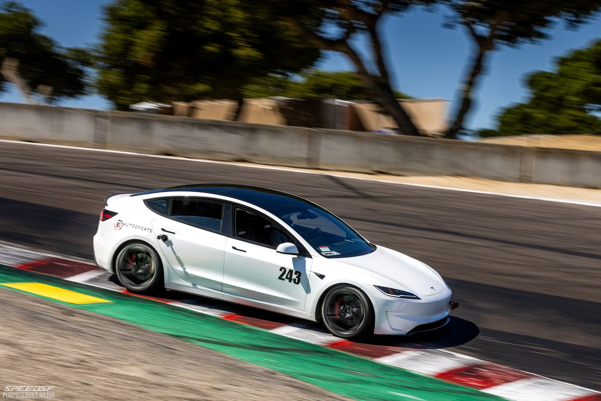 White Tesla Model 3 Performance at speed over track curbing