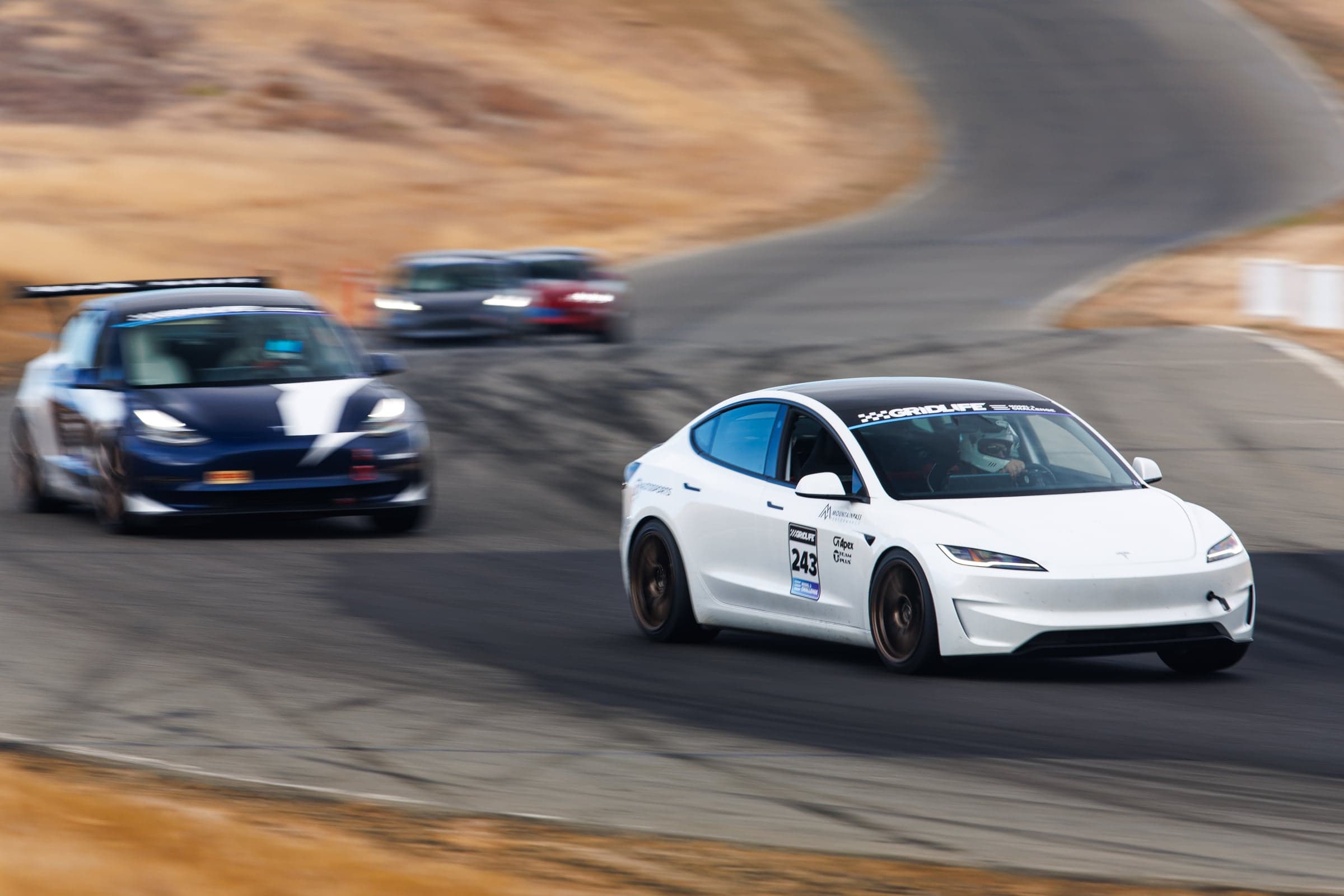 Model 3 Performance leading a group of cars through a corner